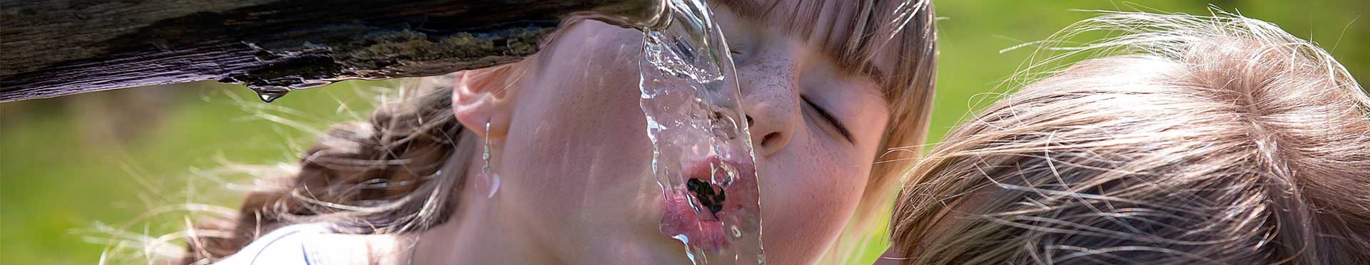 niños bebiendo de fuente de agua clorada